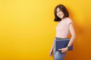 bela mulher asiática estudante universitário feliz em fundo amarelo foto