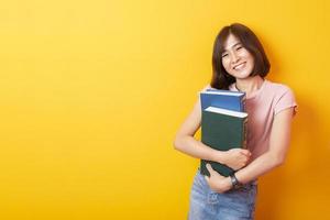 bela mulher asiática estudante universitário feliz em fundo amarelo foto