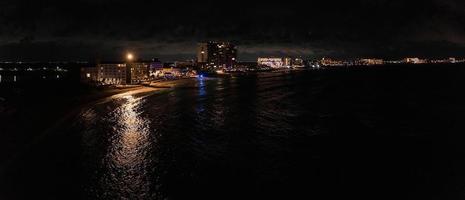vista aérea do hotel de luxo à noite à beira-mar com uma enorme piscina de borda infinita. foto