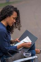 mulher negra com esmalte vermelho refletindo sua resolução de ano novo em um caderno de lista de tarefas com uma caneta preta foto