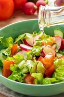 salada de legumes fresca com azeite em uma tigela de cerâmica com fundo de madeira.