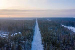 vista aérea na estrada e floresta no inverno. paisagem natural de inverno do ar. floresta sob a neve no inverno. paisagem de drone foto