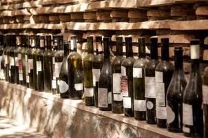 uma fileira de garrafas de vinho em um fundo de parede de tijolos. linha de garrafas de vinho vazias velhas foto