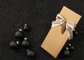livreto de presente com decorações para árvores de Natal em um fundo preto granulado. folheto com fita em fundo preto granulado