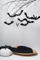 silhuetas de halloween com muitos morcegos pretos em um galho de árvore e uma abóbora em um fundo branco
