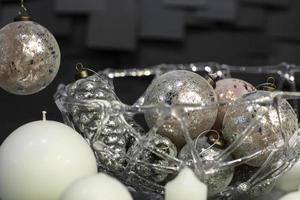 decorações de natal de velas globulares e vasos com brinquedos de natal em um fundo escuro com azulejos foto