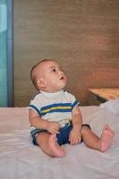 retrato de menino asiático de 6 meses feliz sentado na cama em casa foto