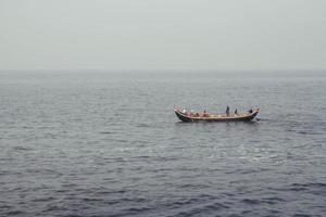 pescadores asiáticos em um barco de madeira navegam no meio do mar. copiar, espaço vazio para texto foto