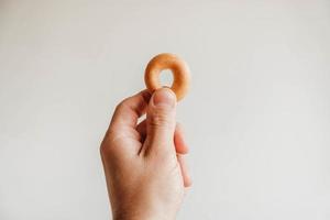 pequeno bagel secando na mão no fundo branco. copiar, espaço vazio para texto foto