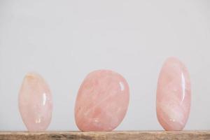 cristais polidos pedra preciosa de quartzo rosa em uma mesa de madeira foto
