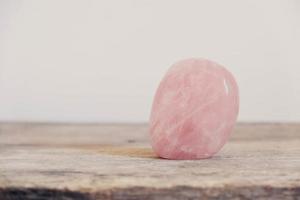 pedra preciosa de quartzo rosa de cristal polido em uma mesa de madeira foto