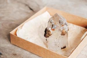 cristal de quartzo em uma caixa de papel kraft com fundo de madeira foto
