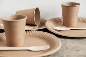 garfos de madeira e copos de papel com pratos em fundo de madeira foto