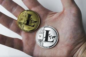 mão segura dois litecoin em um fundo branco. foto