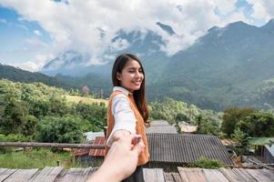 jovem mulher asiática segurando as mãos do namorado enquanto aprecia a vista da montanha na colina no ponto de vista em chiang dao