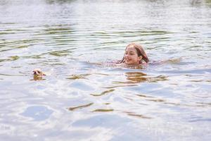 adolescente nada no rio com cachorro chihuahua no verão. criança feliz toma banho. foto