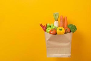 legumes na sacola de compras em fundo amarelo foto