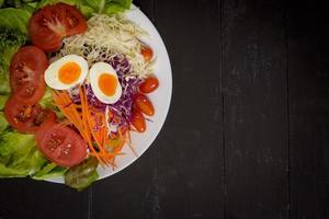 salada de legumes em fundo preto de madeira foto