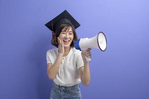 retrato de estudante asiático graduado segurando megafone isolado estúdio de fundo roxo