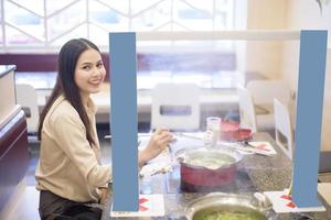 mulher está comendo em restaurante com protocolo de distanciamento social enquanto cidade de bloqueio devido à pandemia de coronavírus foto