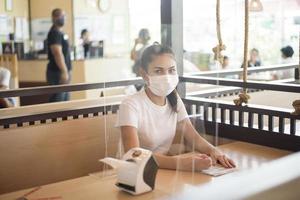 mulher está comendo em restaurante com protocolo de distanciamento social enquanto cidade de bloqueio devido à pandemia de coronavírus foto