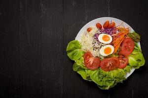 salada de legumes em fundo preto de madeira foto