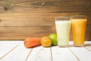 Suco de frutas e legumes dieta saudável pronto para beber na mesa de madeira foto
