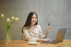 linda mulher está fazendo compras on-line com cartão de crédito no café foto