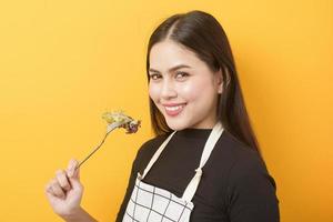 linda mulher saudável está comendo legumes em fundo amarelo foto