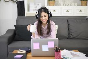 uma bela jovem usando fone de ouvido está fazendo videoconferência via computador em casa, conceito de tecnologia de negócios. foto