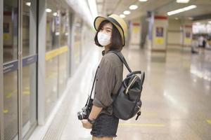 uma jovem e bonita asiática está usando máscara protetora viajando por lugares famosos na cidade de bangkok, nova viagem normal, proteção covid-19, viagens seguras foto