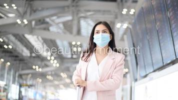 uma mulher de negócios está usando máscara protetora no aeroporto internacional, viaja sob pandemia covid-19, viagens de segurança, protocolo de distanciamento social, novo conceito de viagem normal foto