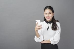 retrato de mulher de negócios linda está usando celular em estúdio foto