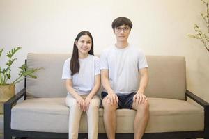 um casal feliz vestindo camisa azul está sentado em um sofá em casa foto