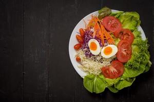 salada de legumes em fundo preto de madeira foto