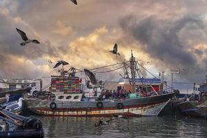 barcos de pesca ancorados ao lado do cais na marina contra dramático céu nublado