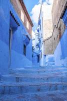 beco estreito da cidade azul com escada que leva a estruturas residenciais em ambos os lados