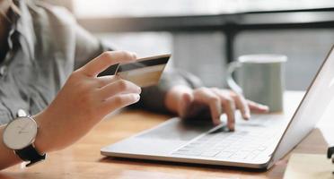 pagamento online, mãos de mulher segurando um cartão de crédito e usando o laptop para fazer compras online com filtro vintage foto