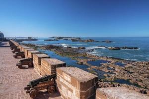 linha de canhões antigos apontados através de fenda na parede na fortaleza histórica foto