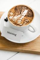 padrão de samambaia café com leite na xícara ao lado do texto de saudação foto