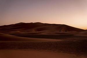 incrível vista das dunas de areia no deserto contra o céu claro durante o pôr do sol foto