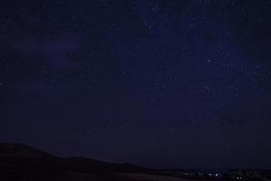 incrível vista do céu estrelado acima da paisagem do deserto durante a noite foto