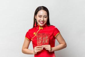 sorrindo feliz mulher asiática em traje tradicional oriental segurando envelopes vermelhos ou ang pao em fundo cinza claro para conceitos de ano novo chinês, texto significa grande sorte grande lucro