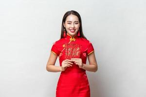 sorrindo feliz mulher asiática em traje tradicional oriental segurando envelopes vermelhos ou ang pao em fundo cinza claro para conceitos de ano novo chinês, texto significa grande sorte grande lucro