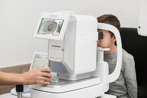 menino é o paciente na recepção no médico oftalmologista. equipamentos oftalmológicos de diagnóstico. conceito de medicina