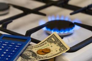 escassez e crise do gás. dinheiro e uma calculadora no fundo de um fogão a gás foto
