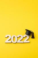 chapéu de graduado com número de madeira 2022 em fundo amarelo. educação, inclinação, formato vertical de conceito de classe 2022 foto