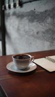 caderno aberto e uma xícara de café na mesa de madeira foto