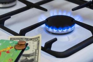 escassez e crise de gás. dinheiro no fundo de um fogão a gás aceso foto
