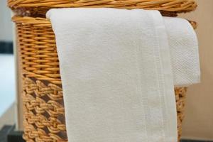 toalha branca em uma cesta de vime no banheiro do hotel foto